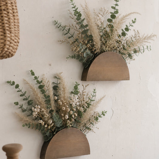 Pair of wooden half-moon wall pockets holding eucalyptus and dried flowers