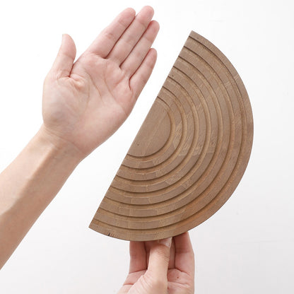 Hand holding one carved wooden half-moon wall pocket to show size